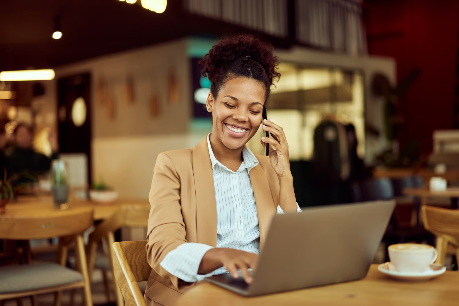 Business professional speaking on the phone while working on a laptop